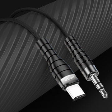 A black Faster M2 audio cable with a USB Type-C connector on one end and a 3.5mm jack on the other, placed on a textured surface.