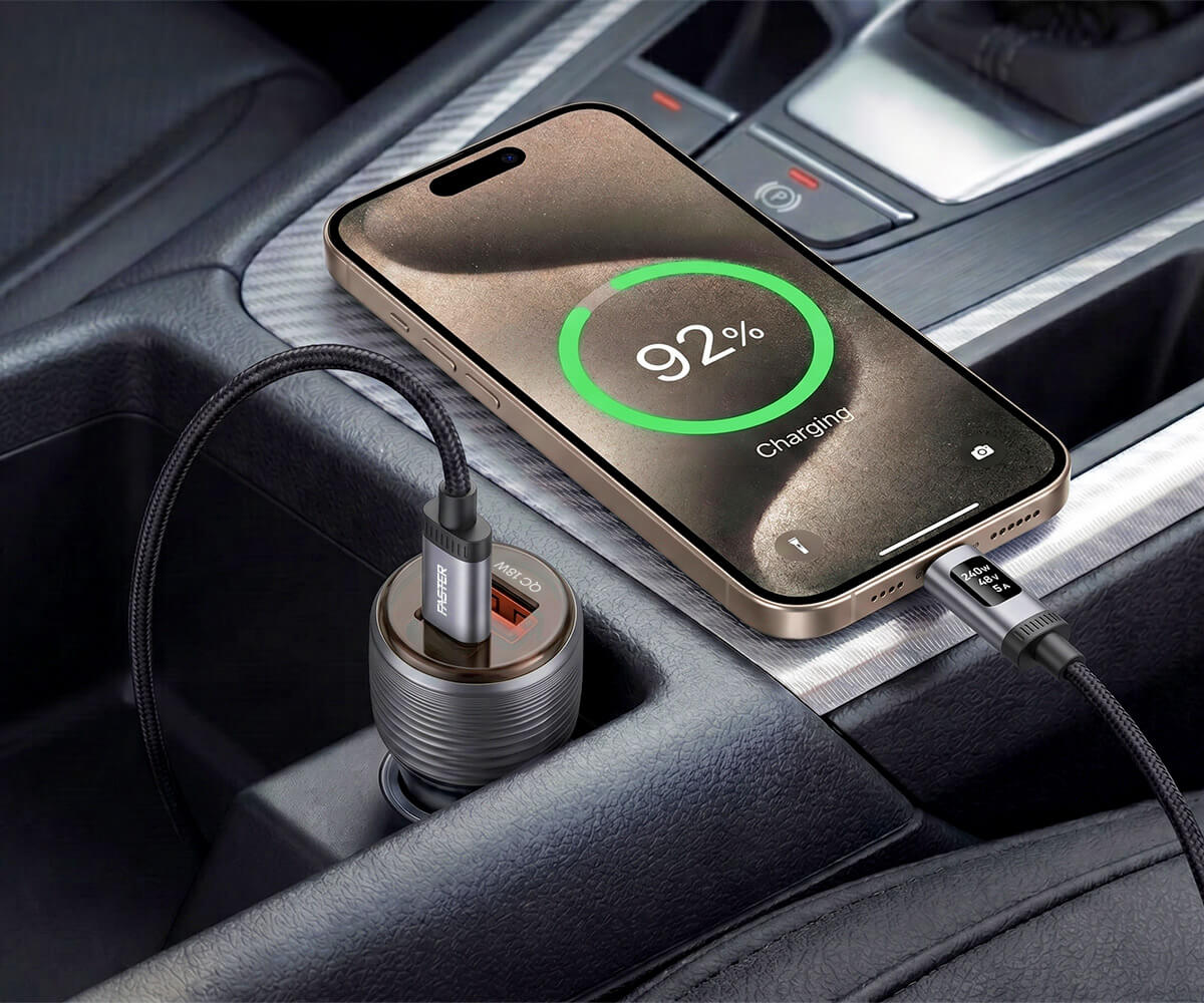 A dual-port car charger plugged into a car's socket, charging a smartphone in the center console. The phone screen displays a 92% battery level with a green ring.