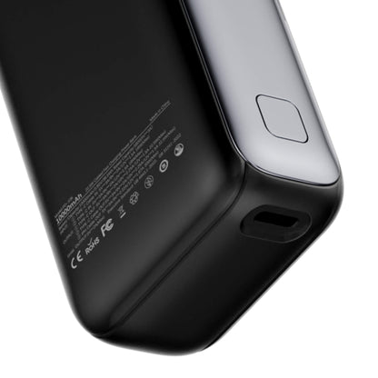 Close-up of the corner of a black portable power bank showing a USB-C port, a charging contact pad, and regulatory text on a white background.